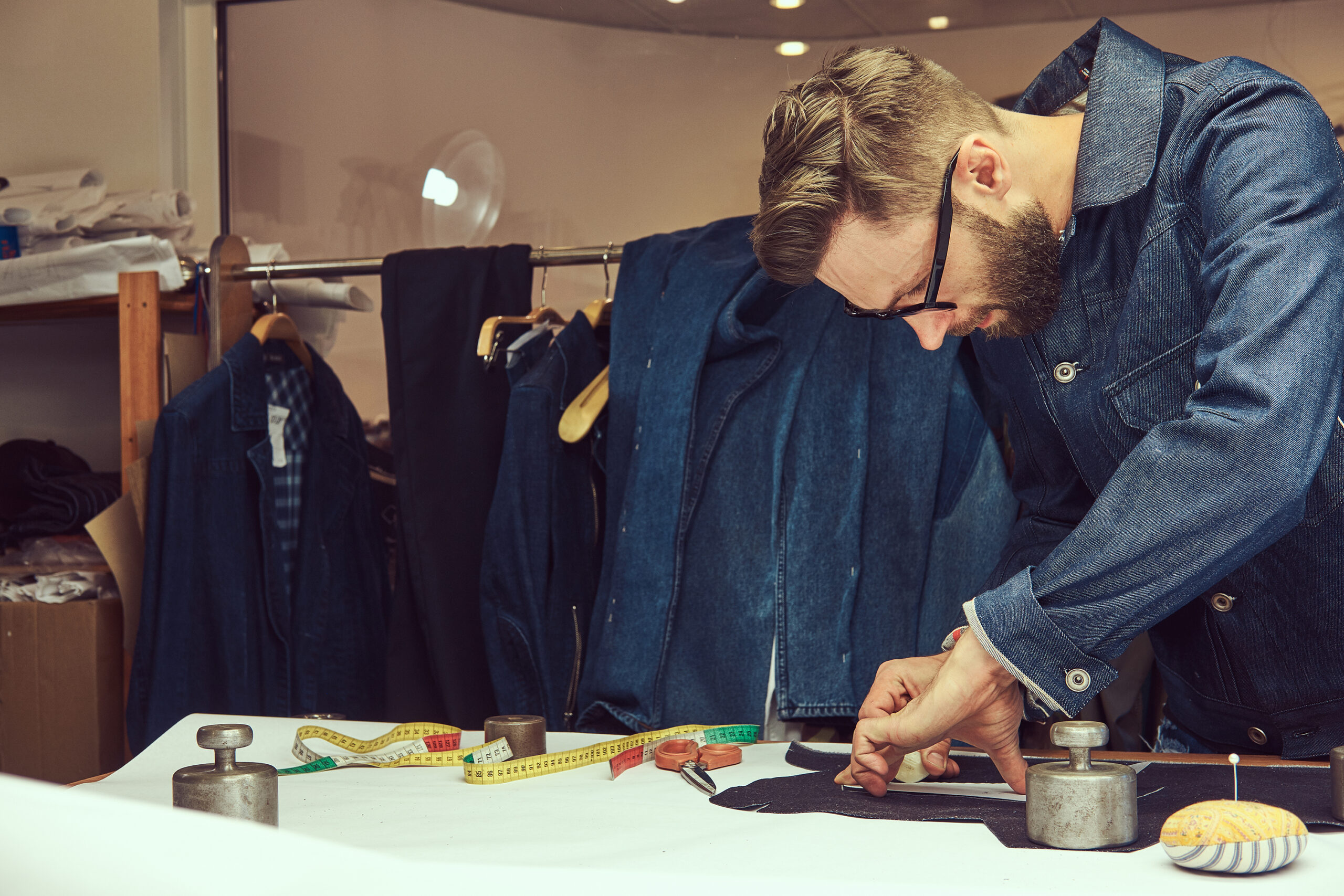 Handsome bearded tailor working with cloth samples at a sewing workshop.